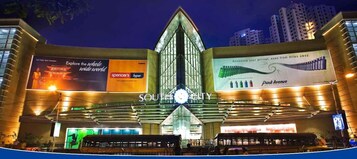 Un bâtiment moderne orné de grandes enseignes publicitaires faisant la promotion de destinations de voyage et d’un panneau bien visible indiquant « SOUTH CITY ».