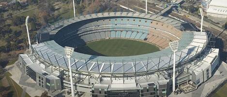 An aerial view of a stadium with a central field, surrounding seating, and multiple light towers.