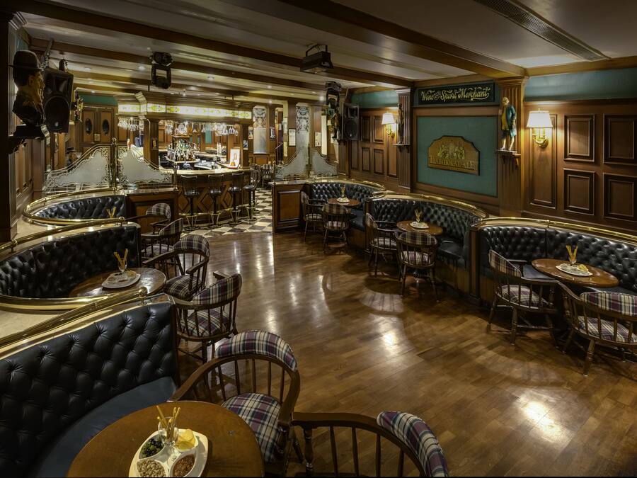 Una zona de bar con cabinas de cuero, mesas de madera y taburetes.