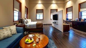 Amplia habitación de hotel con una cama grande, televisión, escritorio y kitchenette.