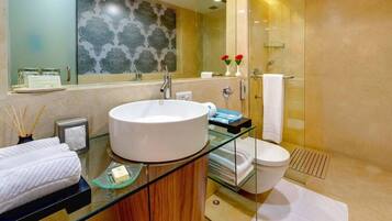 A modern bathroom with a large white sink, glass shower enclosure, and a glass-topped vanity.