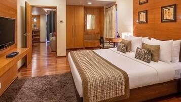 Habitación de hotel con una cama grande, un televisor sobre un mueble de madera, un escritorio con una silla y un armario.