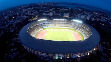 Et stort stadion med flere niveauer af sæder og en central græsbane.