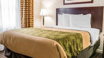 Een hotelkamer met een groot bed, een hoofdeinde, een lamp en een schilderij aan de muur.