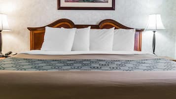 Una cama bien hecha con una colcha estampada y un cabecero de madera. Hay dos lámparas de noche y un cuadro en la pared sobre la cama.