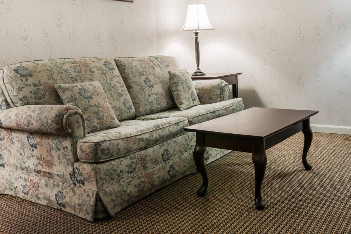 A living room with a floral sofa, a wooden coffee table, a lamp, and a framed picture on the wall.