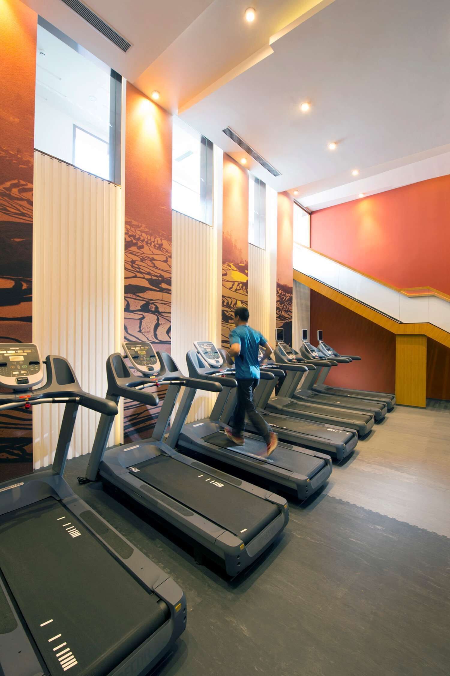 A gym with treadmills and a person running.