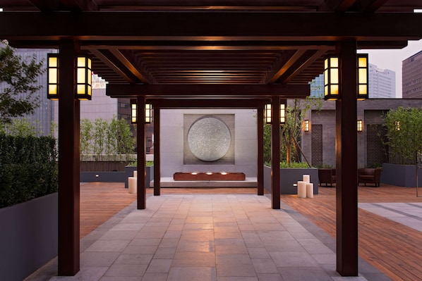 A covered outdoor area with a central seating area, wooden flooring, and lantern-style lighting. - Hilton Beijing (Beijing)