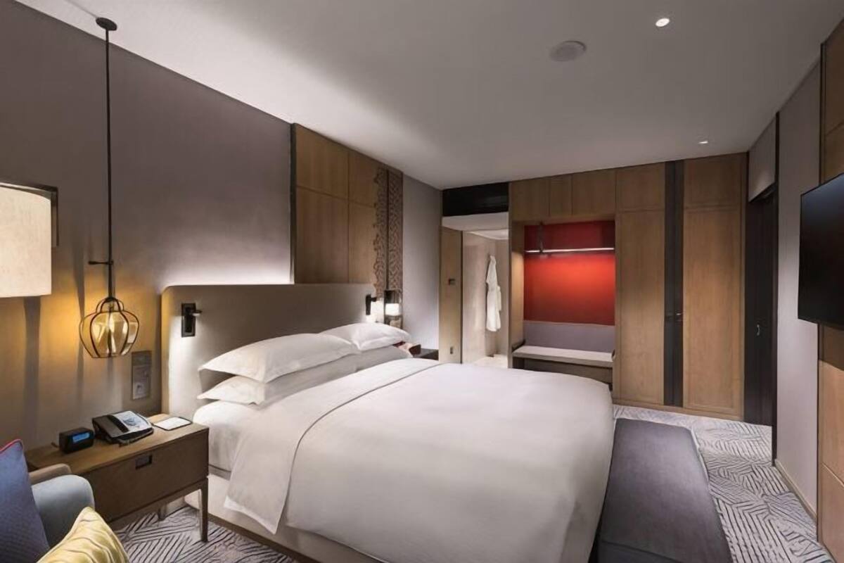 Una habitación de hotel moderna con una cama grande, mesitas de noche, un escritorio y un televisor.