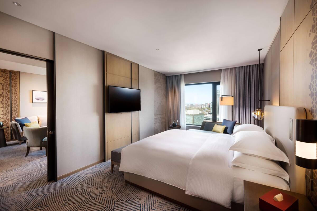 Habitación de hotel con una cama grande, televisor de pantalla plana, vistas a la ciudad y un diseño moderno.