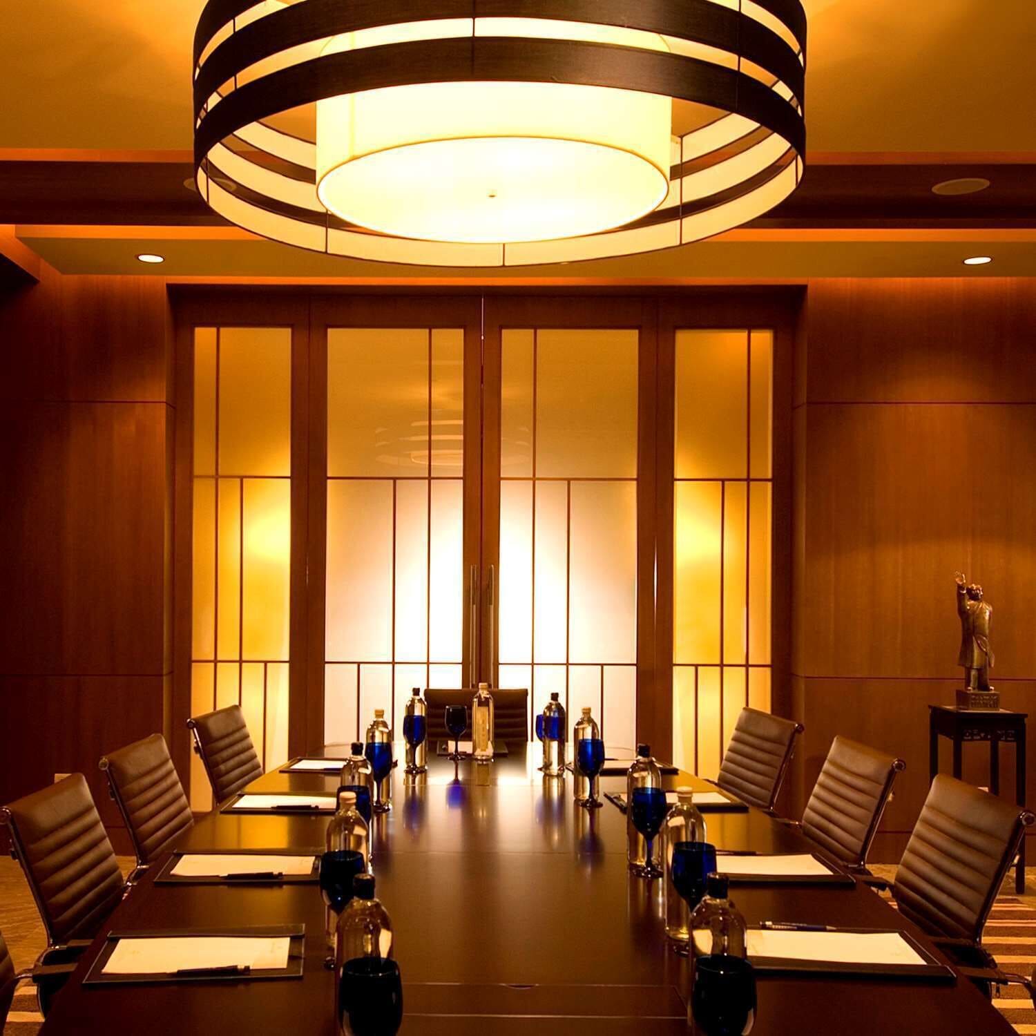 Une salle de conférence avec une longue table, des chaises et un grand lustre.