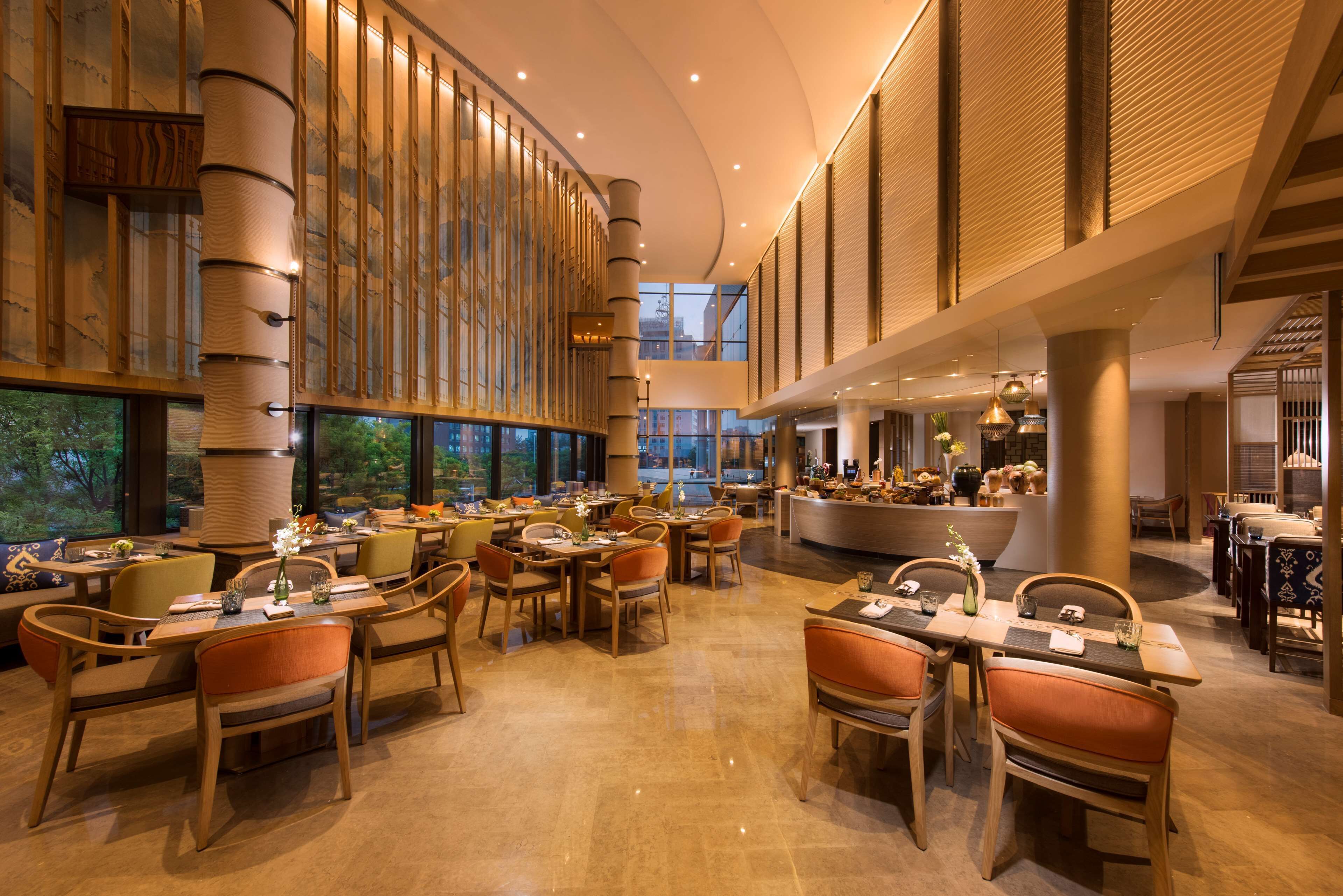 A spacious restaurant with high ceilings, large windows, and a central bar area.
