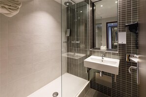 A modern bathroom with a glass-enclosed shower, a white sink, and a mirror.