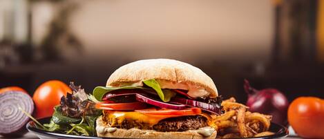 A plate with a burger, salad, and onion rings.