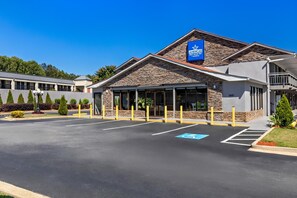 A hotel with a stone facade, a blue sign, and a parking lot with handicapped spaces. - Americas Best Value Inn Douglasville (Douglasville)