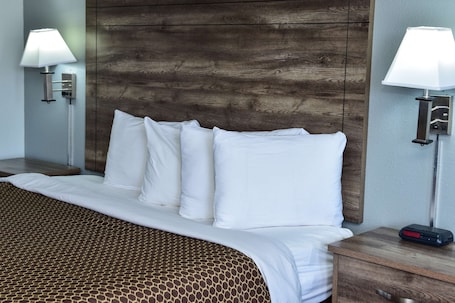 A hotel room with a wooden headboard, white bedding, and two bedside lamps.