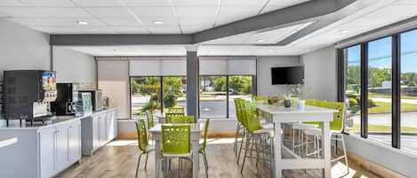 Interior moderno de una cafetería, con mostrador, zona de estar y ventanas amplias.