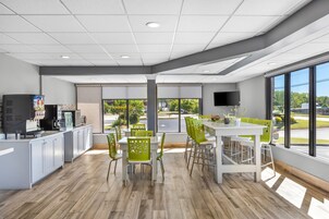 Interior moderno de una cafetería, con mostrador, zona de estar y ventanas amplias.