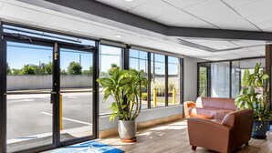 A spacious lobby with large windows, a reception desk, and a seating area with two sofas. - Americas Best Value Inn Douglasville (Douglasville)