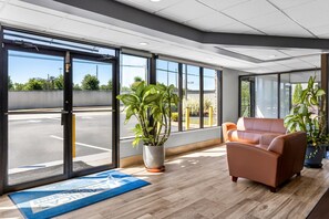 A spacious lobby with large windows, a reception desk, and a seating area with two sofas.