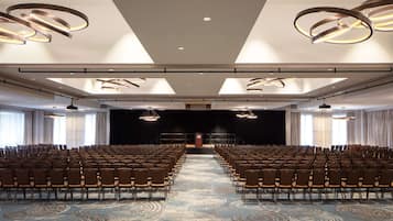A large conference room with rows of chairs, a stage, and modern lighting fixtures.