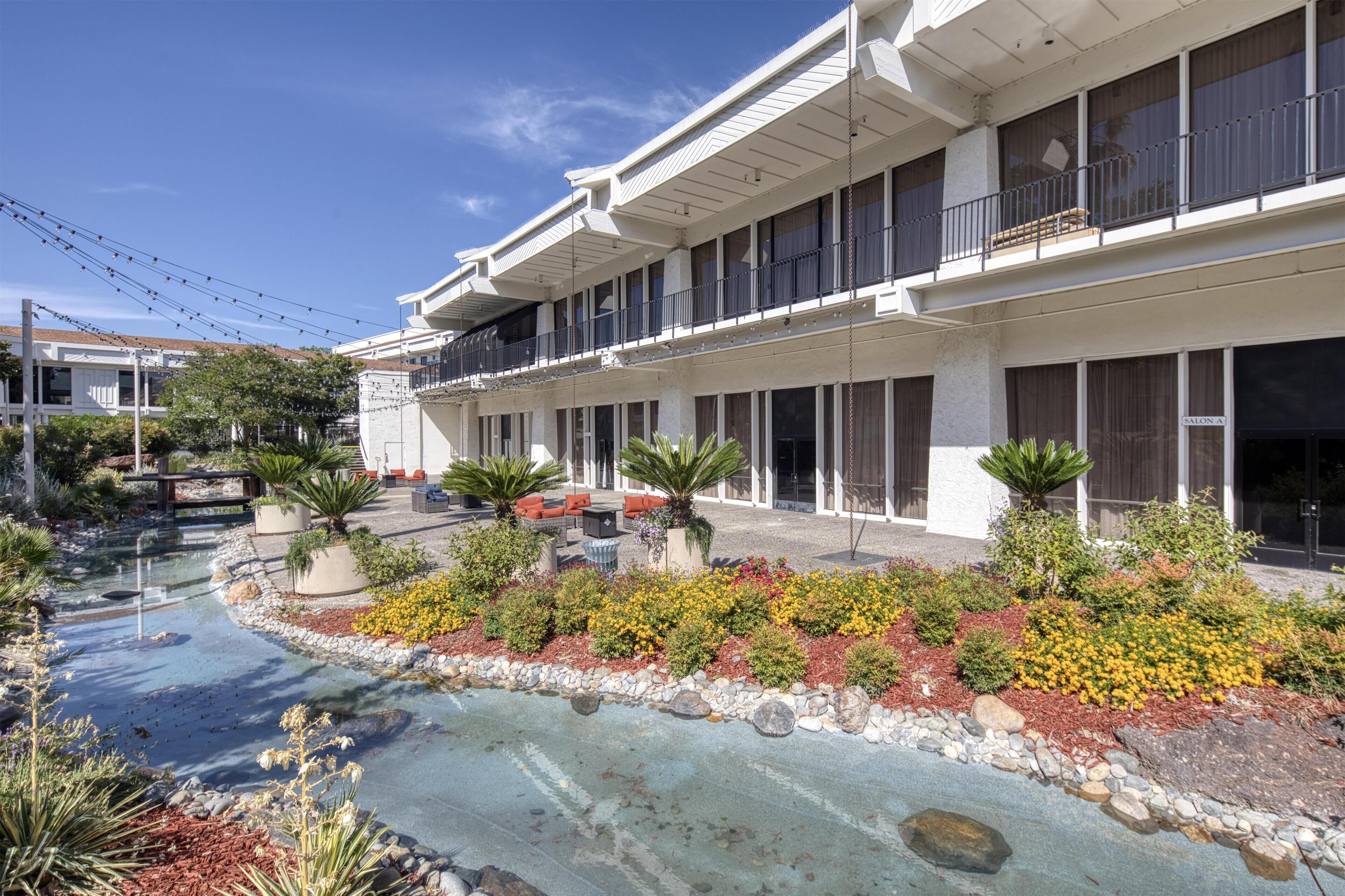A hotel with a pool, outdoor seating, and a garden area.