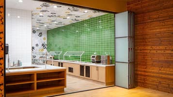 A modern kitchen with wooden cabinets, a green tiled backsplash, and a built-in refrigerator.