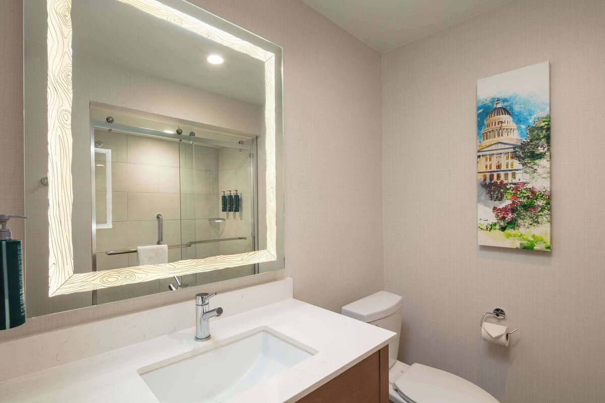 A modern bathroom with a large mirror, a sink, and a toilet.