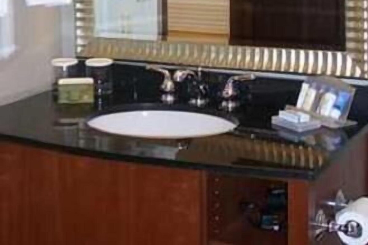 A bathroom with a large mirror, a sink, and a towel rack.
