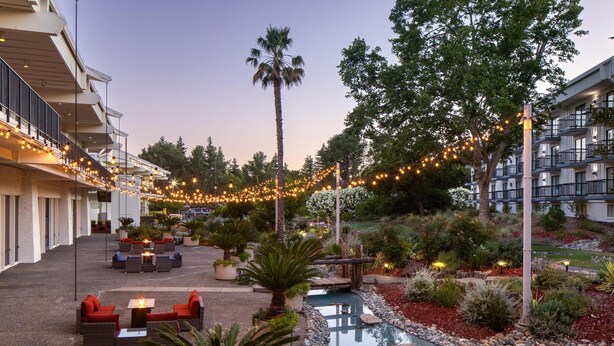 A hotel courtyard with outdoor seating, a small pool, and string lights. - DoubleTree by Hilton Sacramento (Sacramento)