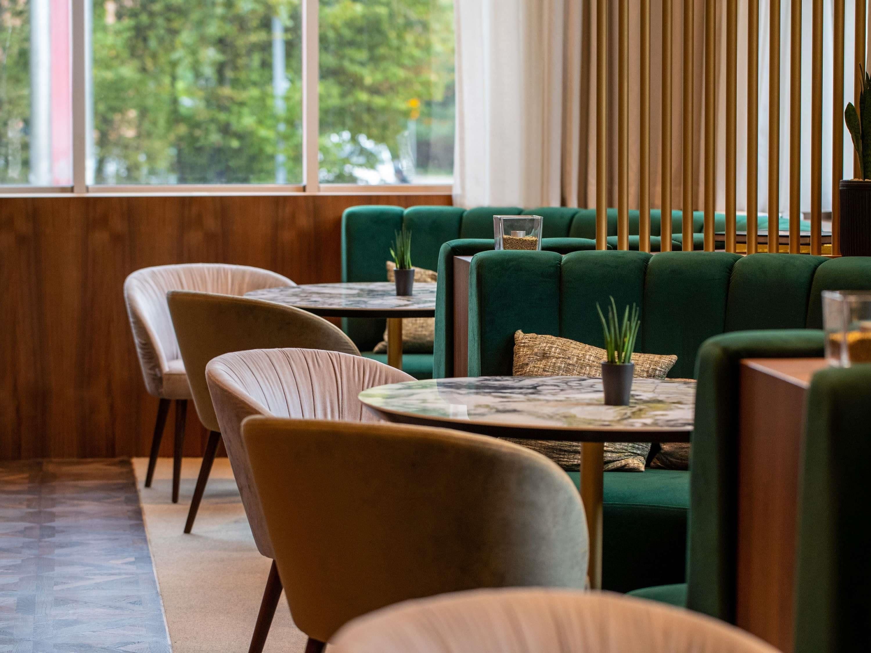 Un interior moderno con asientos tapizados en verde, detalles de madera y vistas a zonas verdes.