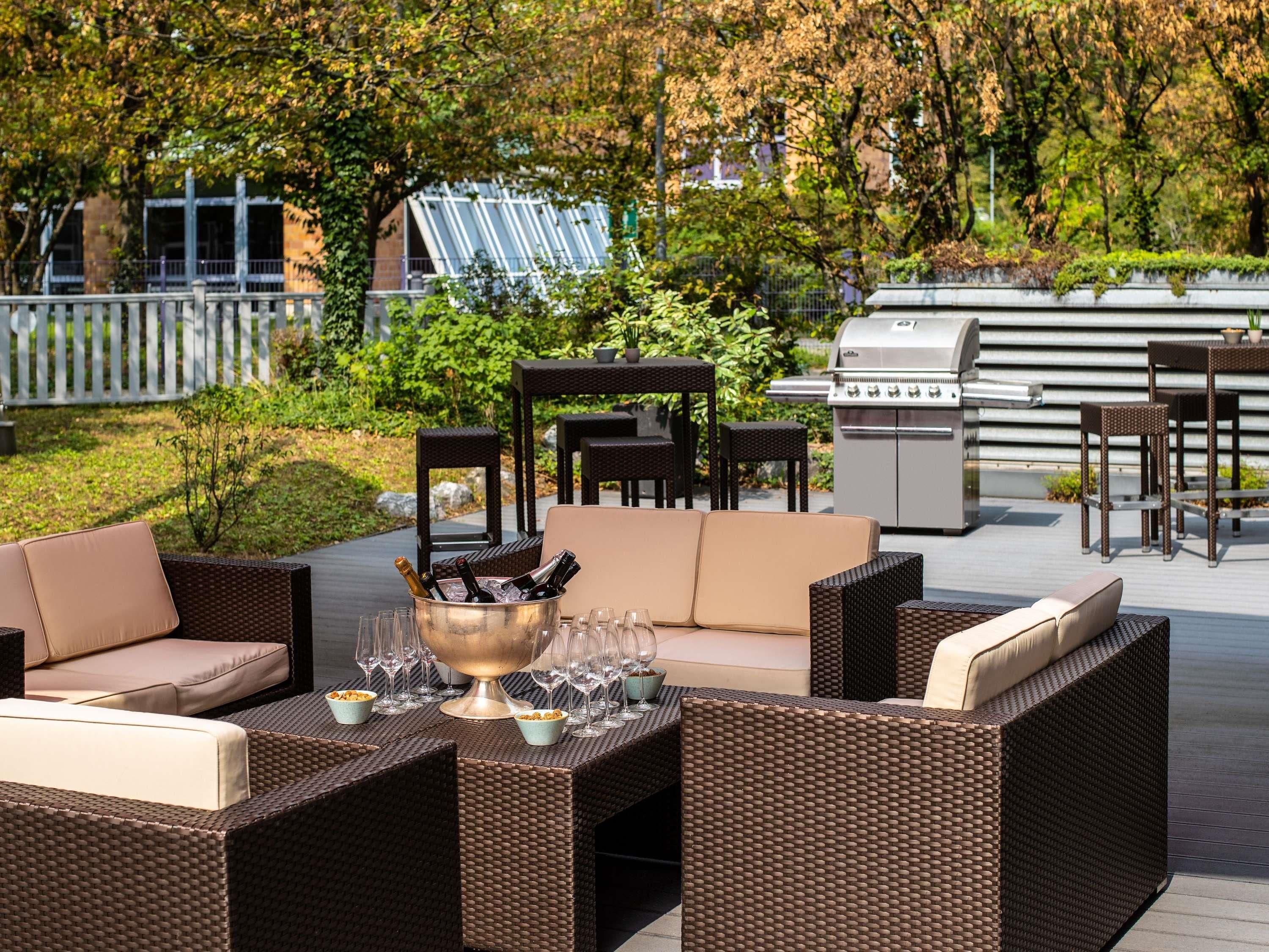 Une terrasse extérieure avec des meubles en osier, un barbecue et un verre de vin.