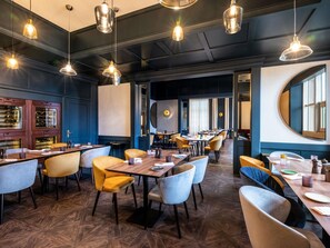 A restaurant with multiple dining tables and chairs, a wine display, and pendant lighting. - Pullman Stuttgart Fontana (Stuttgart)