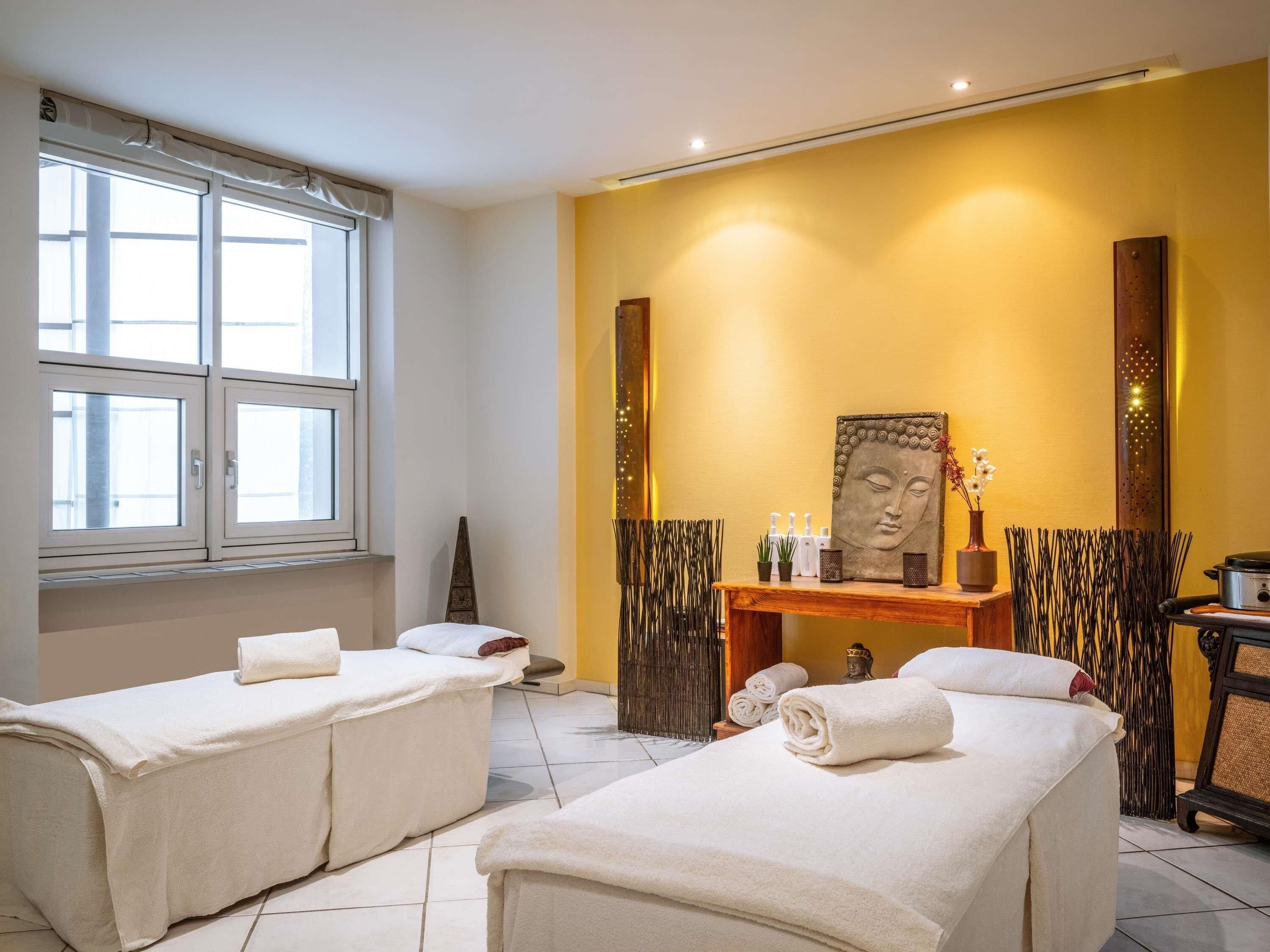 A spa room with two massage tables, a Buddha statue, and a wall-mounted picture.