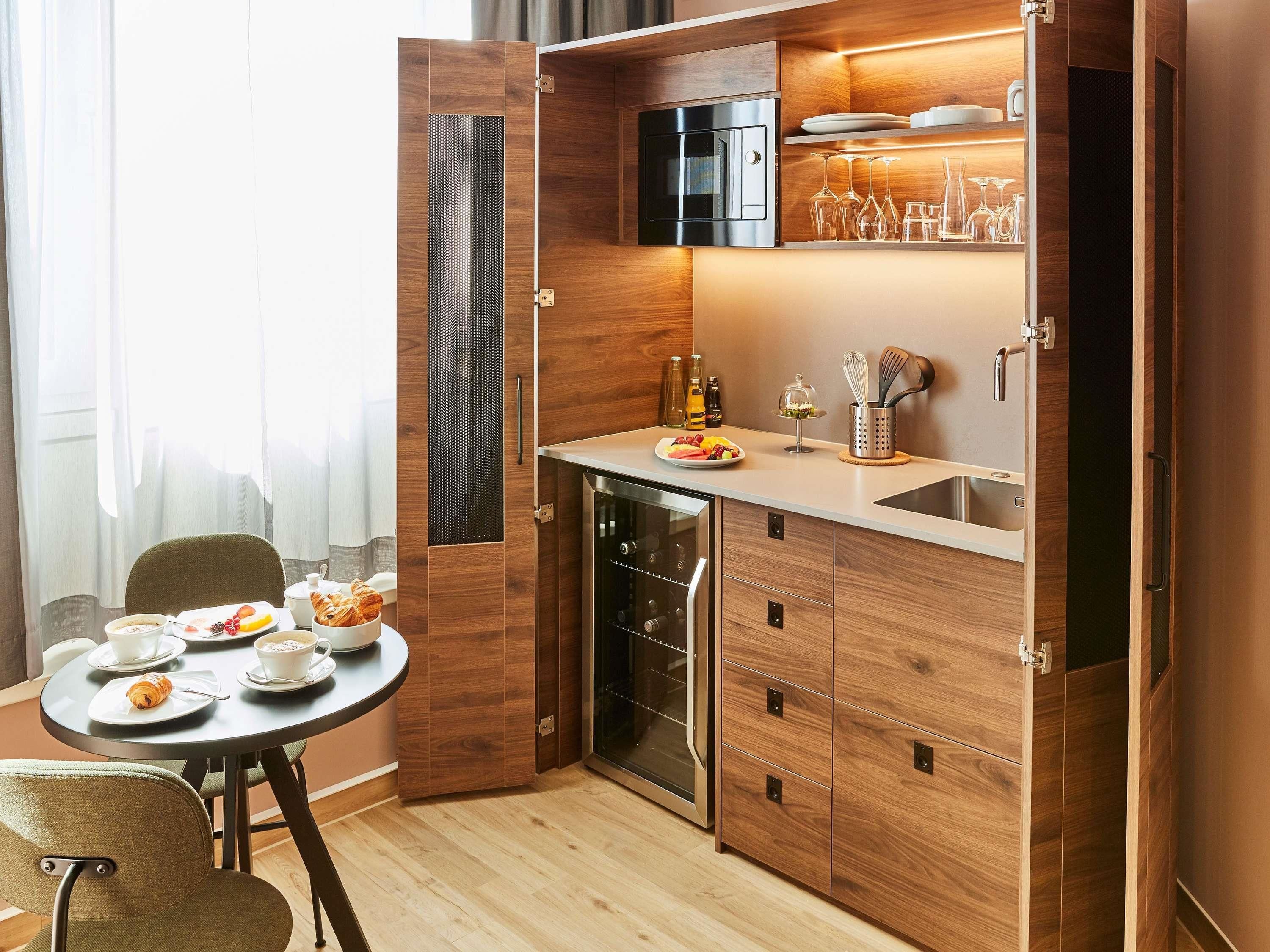 A compact kitchen with a built-in oven, a dishwasher, and a small dining area with a table set for breakfast.