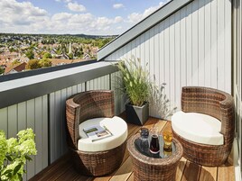 En balkon med fletstole, et lille bord og en potteplante.