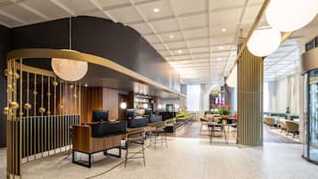 A modern hotel lobby with a bar area, seating, and a large window.