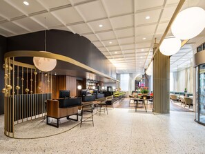Una hall d'hotel moderna con zona bar, posti a sedere e un'ampia finestra.