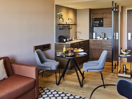 Una cocina moderna con comedor, que incluye una isla central, sillas y una cafetera.