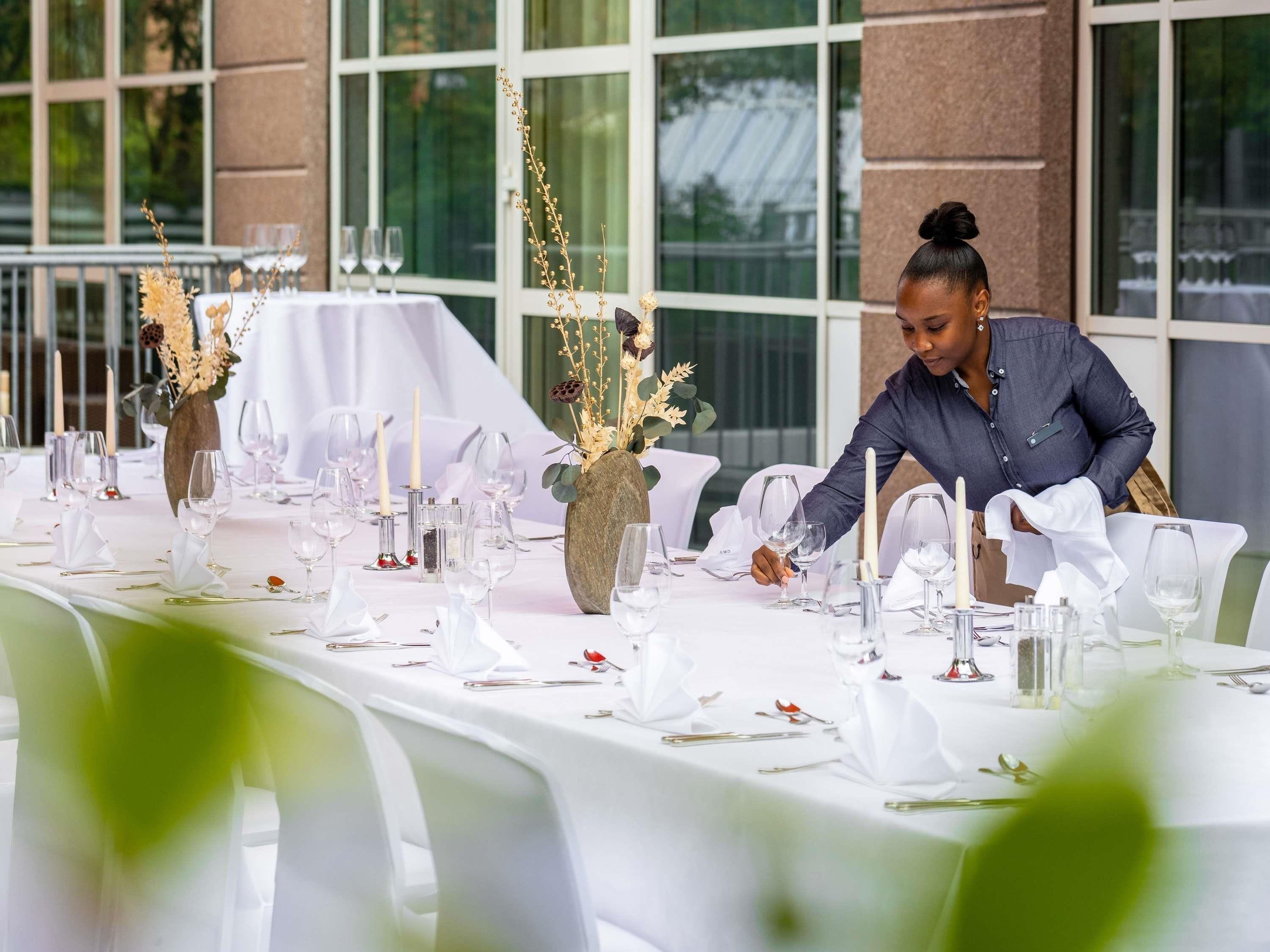A table set for a formal event with white tablecloths, glassware, and floral centerpieces.