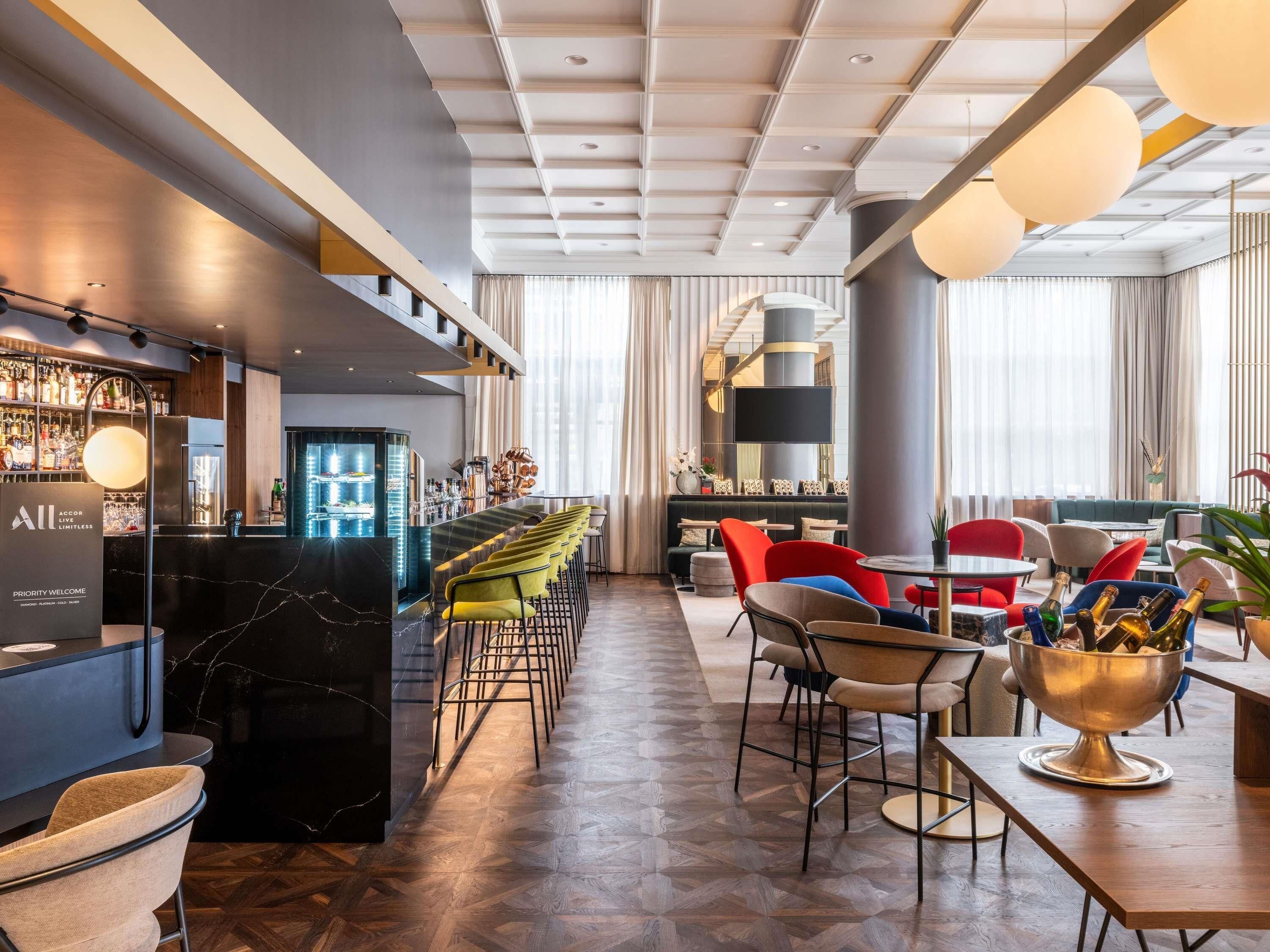 En moderne hotellobby med barområde, siddepladser og en trappe.