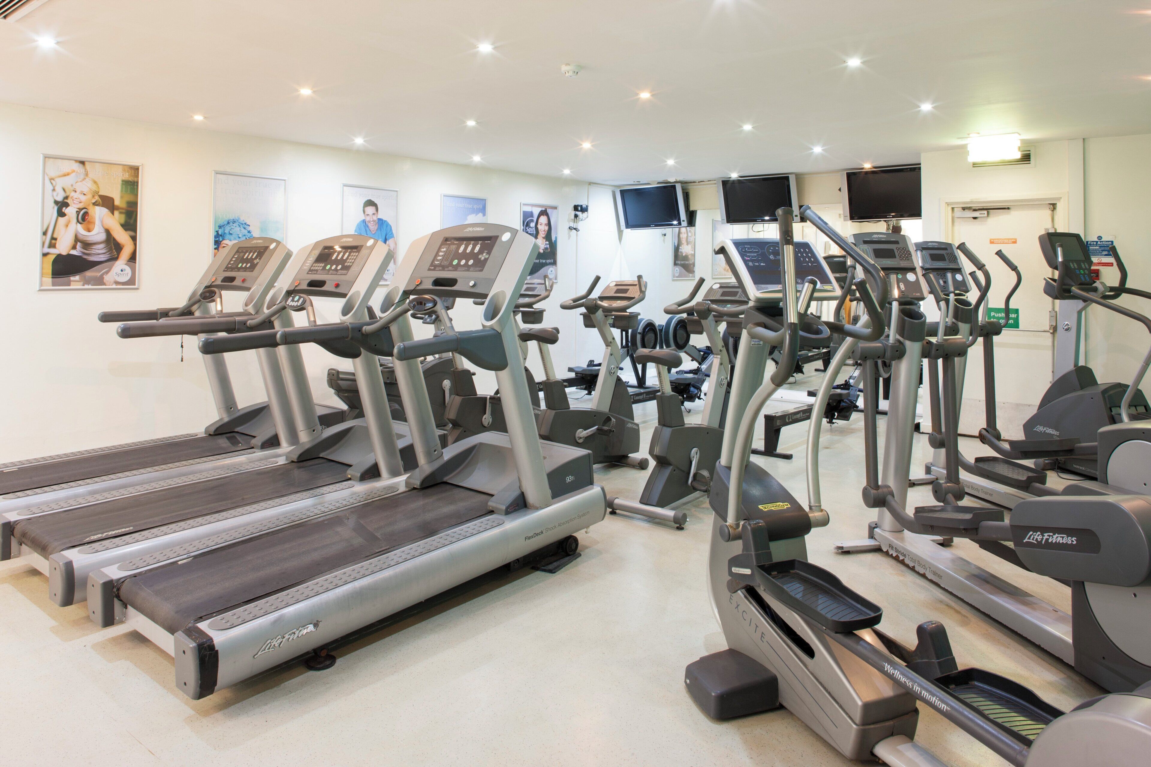 A gym with multiple treadmills, ellipticals, and a stationary bike.