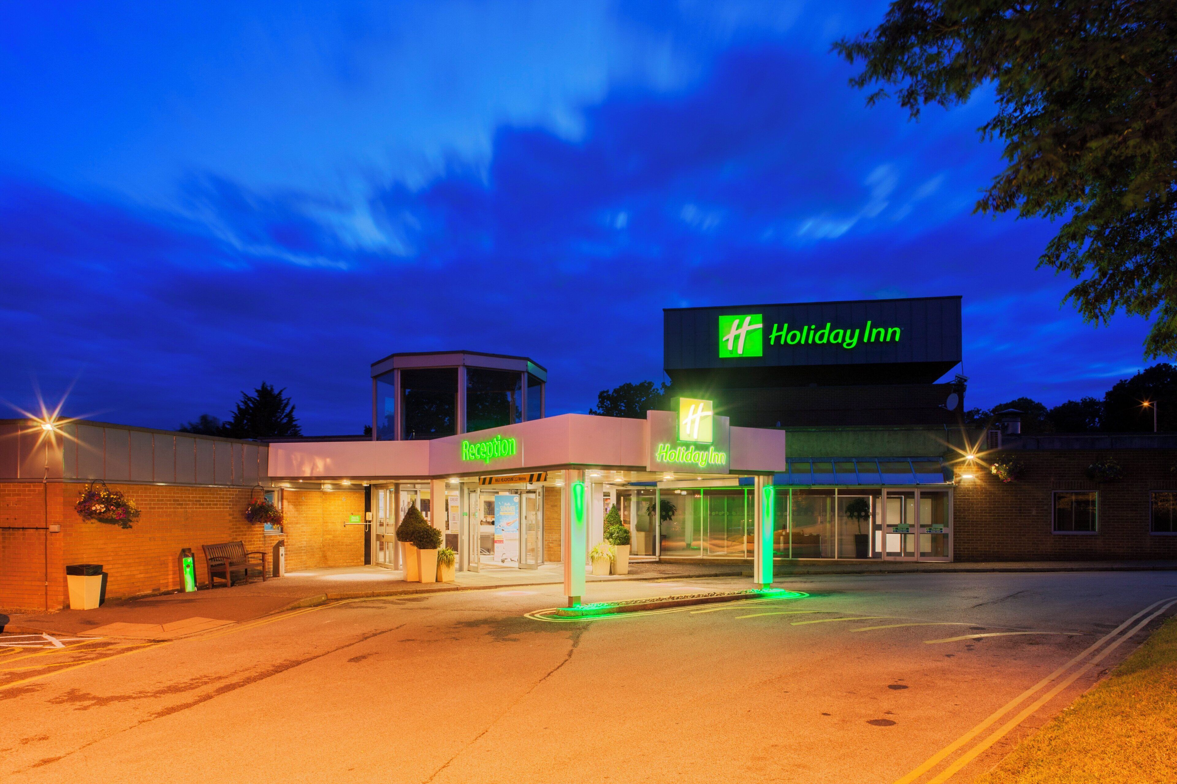 A Holiday Inn with a reception area, a small tower-like structure, and a parking lot.