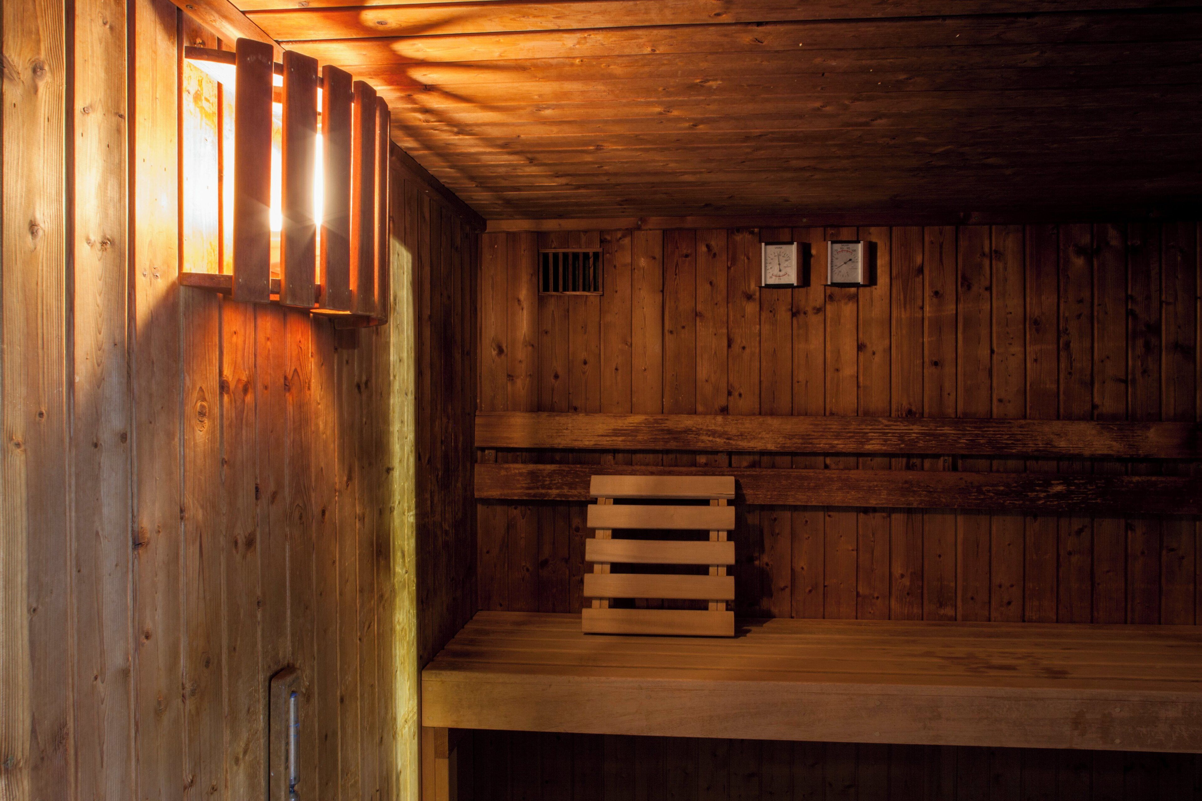 A wooden interior with a bench and two wall-mounted clocks.