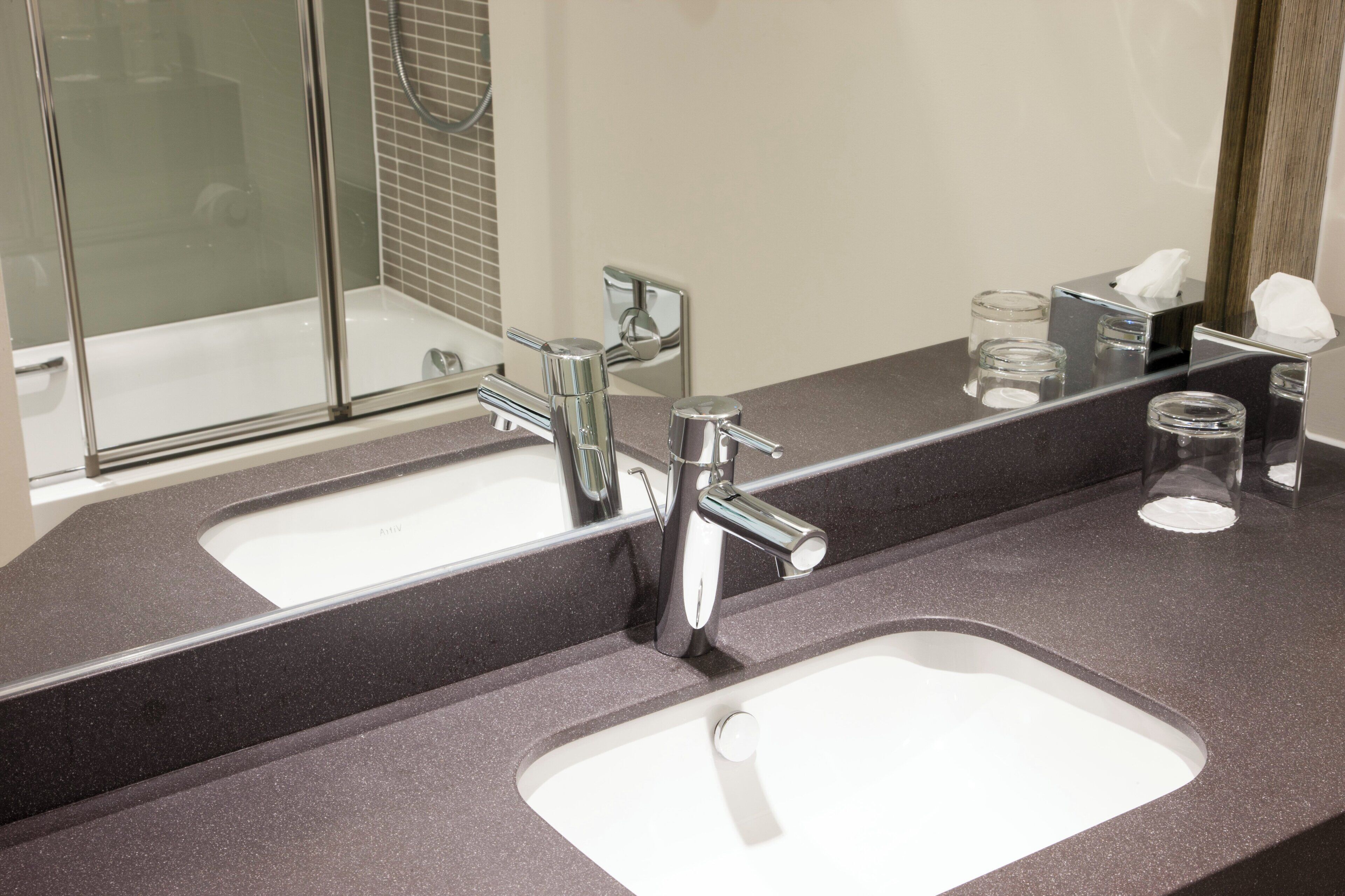 Une salle de bain avec deux lavabos, un miroir et un espace douche.