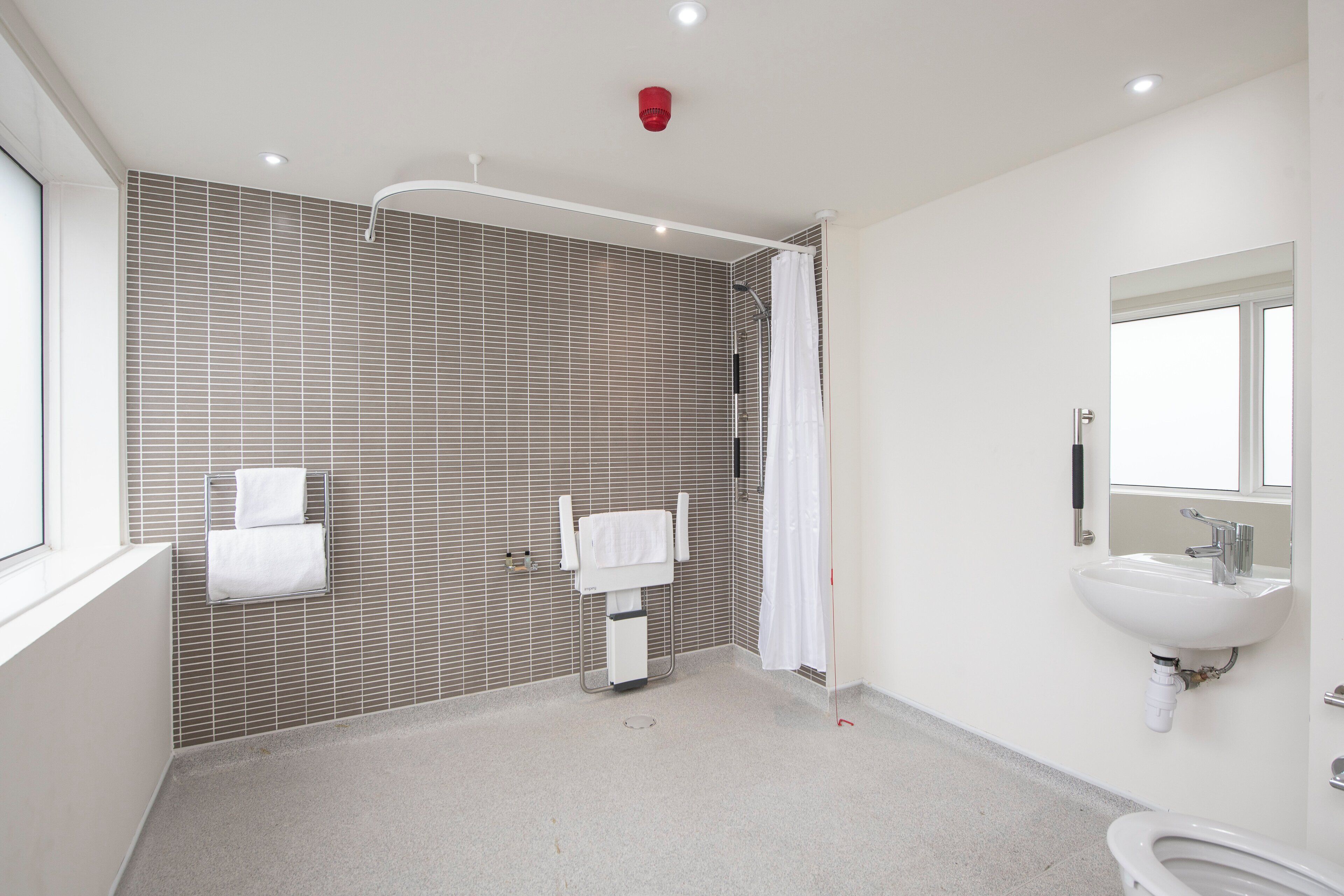 A modern bathroom with a shower, a sink, and a toilet.