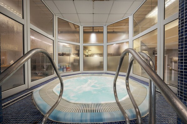 A hot tub with metal railings, surrounded by frosted glass windows and a tiled floor. - Holiday Inn Norwich by IHG (Norwich)