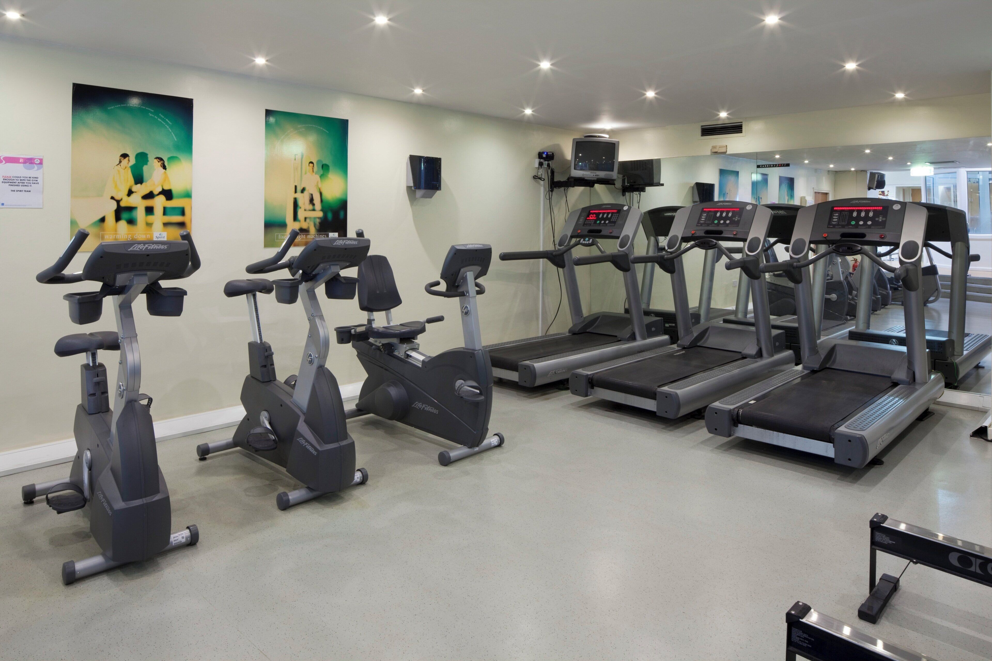 A gym with multiple cardio machines including treadmills and stationary bikes.