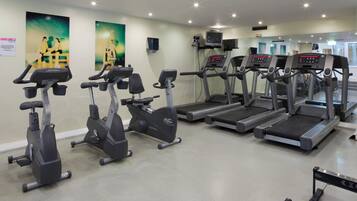 Un gimnasio con varias máquinas de cardio, incluyendo cintas de correr y bicicletas estáticas.