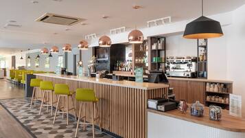 A modern bar area with a wooden counter, bar stools, and a coffee machine.